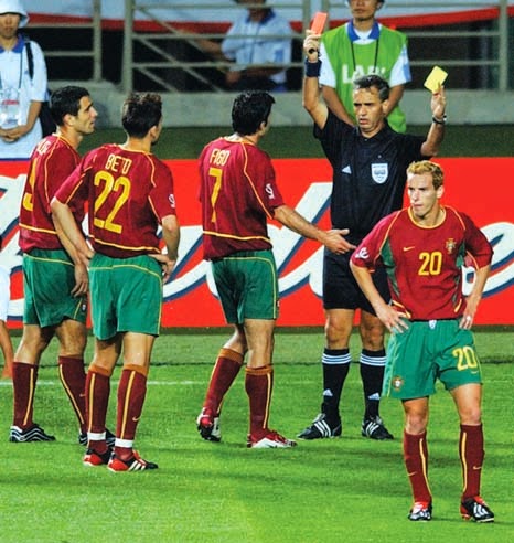 Referee Angel Sanchez flashes a red-card to Portugal's Beto (2/L#22) after he received his second yellow-card during the game as Portugal's Luis Figo (3/L) disputes the call, 14 June 2002 at the Incheon Munhak Stadium in Incheon, prior to first round Group D action between Portugal and Korea in the 2002 FIFA World Cup Korea/Japan. Portugal had two players sent off in their 1-0 defeat to Korea.  At the left is Pauleta and on the right is Petit. AFP PHOTO/PASCAL GUYOT