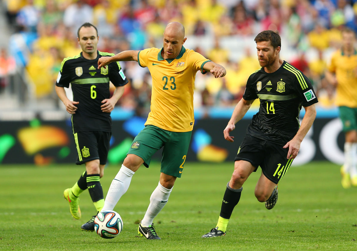 CURITIBA, BRAZIL - JUNE 23:  Mark Bresciano of Australia controls the ball against Andres Iniesta (L) and Xabi Alonso of Spain during the 2014 FIFA World Cup Brazil Group B match between Australia and Spain at Arena da Baixada on June 23, 2014 in Curitiba, Brazil.  (Photo by Cameron Spencer/Getty Images) ORG XMIT: 491933361