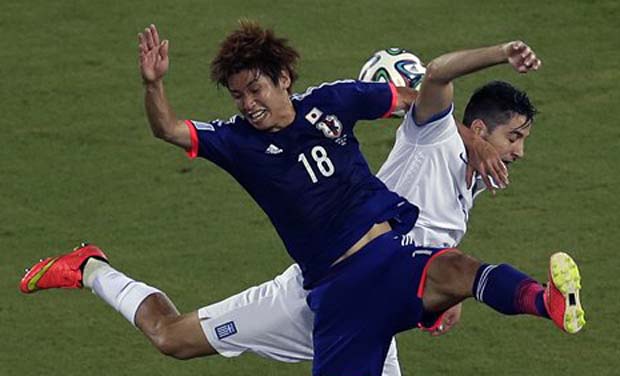 Japan's Yuya Osako, front, and Greece's Kostas Manolas challenge for the ball during the group C World Cup soccer match between Japan and Greece at the Arena das Dunas in Natal, Brazil, Thursday, June 19, 2014. (AP Photo/Hassan Ammar)